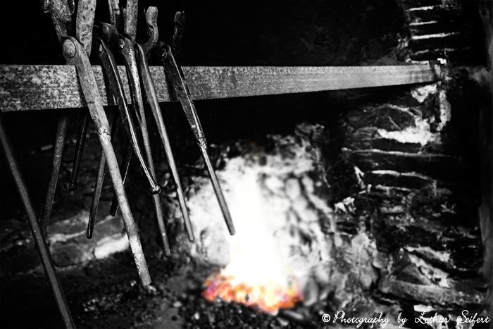 Schmiedezangen mit Schmiedefeuer in einer alten Schmiede. Fotografie von Lothar Seifert
