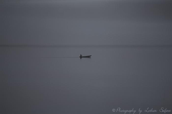 Ein Boot auf einem See einsam im Nebel. Fotografie von Lothar Seifert