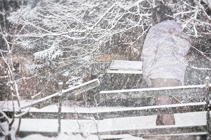 Frau im Schnee vor einem alten Haus. Fotografie von Lothar Seifert